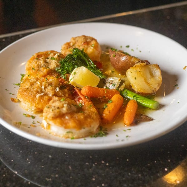 Sapore Italian Cafe's golden-brown scallops with roasted potatoes, carrots, broccoli, and a lemon wedge.