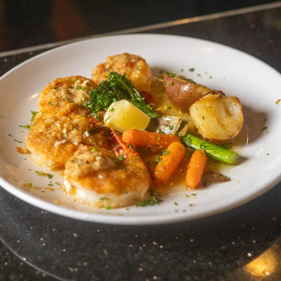 Sapore Italian Cafe's golden-brown scallops with roasted potatoes, carrots, broccoli, and a lemon wedge.
