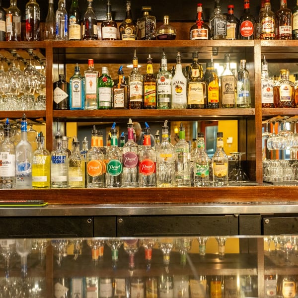 A well-stocked bar with various liquor bottles and glassware on wooden shelves at Sapore Italian Cafe.