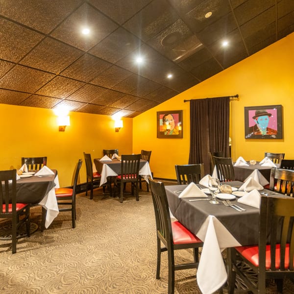 Sapore Italian Cafe dining room with yellow walls, black tables, red chairs, and pop art.