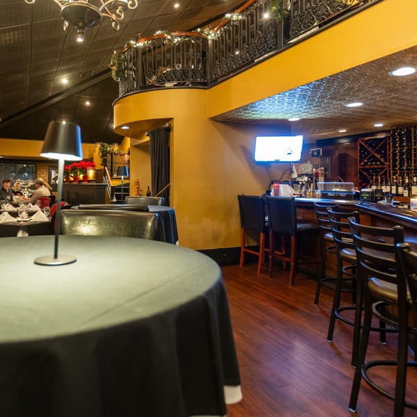 Sapore Italian Cafe's interior features a bar, dining tables, and a festive balcony with string lights.