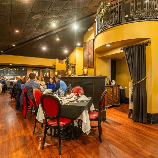 Diners seated at tables with red chairs and black tablecloths in Sapore Italian Cafe's warm, inviting dining room.